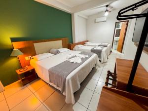 two beds in a room with green walls at Parque Hotel Cordeiro in Cordeiro