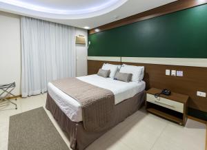 a bedroom with a large bed and a green wall at Centromar Hotel in Balneário Camboriú +59 photos