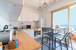 a kitchen with white cabinets and a table with chairs at Luxury Monte Carlo- Seaview, Champagne & AC in Beausoleil