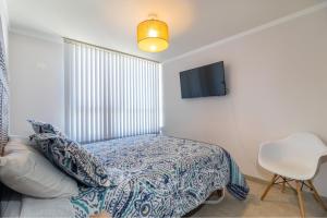 ein Schlafzimmer mit einem Bett und einem Fernseher an der Wand in der Unterkunft Disegni 06 - Departamento vista al mar y Casino Enjoy La Serena in Coquimbo + 23 Fotos