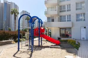 ein Spielplatz mit einer roten Rutsche vor einem Gebäude in der Unterkunft Disegni 06 - Departamento vista al mar y Casino Enjoy La Serena in Coquimbo