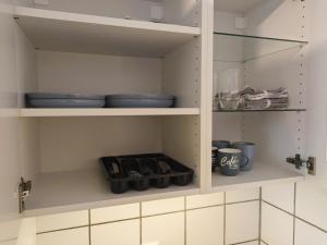 a cupboard with plates and bowls and other kitchen items at CityWest Apartment - mit Balkon in Bielefeld