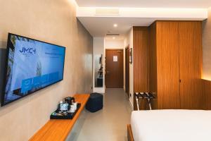 a room with a bed and a tv on a wall at J Maluni City Hotel in Rome