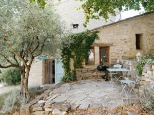 ein Steinhaus mit einem Tisch und Stühlen davor in der Unterkunft Cute stone cottage in Provence in Rivest-Saint-Martin