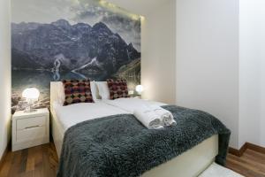 1 dormitorio con 1 cama grande y una pintura en la pared en VIP Apartamenty Gorące Źródła, en Zakopane
