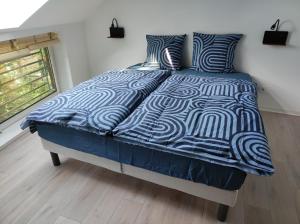 1 cama con edredón azul y blanco en un dormitorio en Gîte Aux murmures de la Streng, en Ribeauvillé