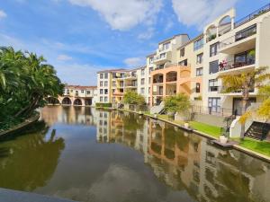 Un río con edificios de apartamentos al lado de un cuerpo de agua. en Capri 504, Island Club, Century City, en Ciudad del Cabo