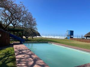 a swimming pool with a blue slide in a park at Wooden house lodge in KuGqangushe