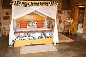 a bedroom with a bed with a canopy with zebra pillows at Akagera Rhino Lodge in Rwinkwavu