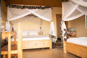 a bedroom with two beds and a canopy bed at Akagera Rhino Lodge in Rwinkwavu