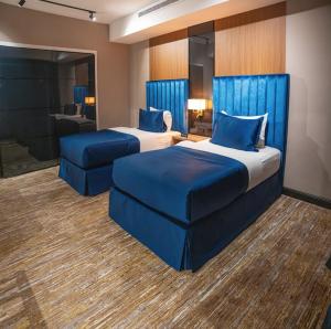 two beds with blue pillows in a hotel room at Dana Hotel in Buraydah +74 photos