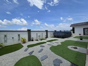 un patio con erba e rocce e un edificio di The Bangau Cottage a Sungai Petani