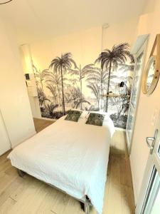 a bedroom with a bed with palm trees on the wall at Studio Chic & Balcon - Hypercentre - Gare - Metro in Toulouse