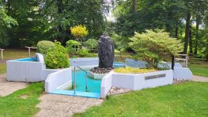 a statue in a garden with some bushes and trees at Ferienwohnung am Kurpark Ehlscheid in Ehlscheid