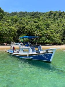 a blue and white boat in the water next to a beach at Passeio de barco em Paraty in Paraty