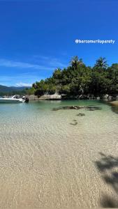 a beach with sand and trees in the water at Passeio de barco em Paraty in Paraty