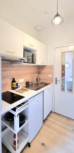 a kitchen with white cabinets and a sink at Studio Chic & Balcon - Hypercentre - Gare - Metro in Toulouse