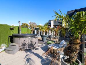 a patio with a hot tub and palm trees at Rye Croft in Neston
