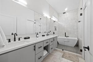 a white bathroom with a tub and a sink and a bath tub at Rainey St Retreat - Cowboy Pool & Urban Chic in Austin +26 photos