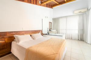 a bedroom with a large bed with a wooden headboard at Pousada Pedra da Ilha in Penha