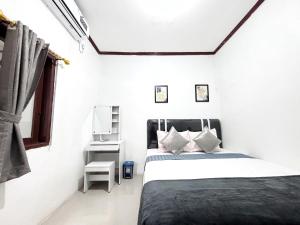 a white bedroom with a bed and a window at Semarang Inn Syariah in Semarang