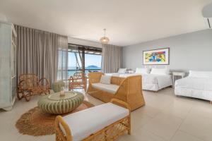 a bedroom with two beds and a living room at Pousada Pedra da Ilha in Penha