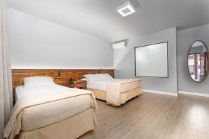 a bedroom with two beds and a mirror at Pousada Pedra da Ilha in Penha