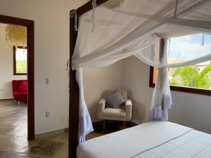 a bedroom with a canopy bed and a chair at Exclusive House Preá in Cruz +55 photos
