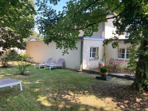 a white house with purple chairs in the yard at Le Moulin Neuf in Saint-Antoine-Cumond