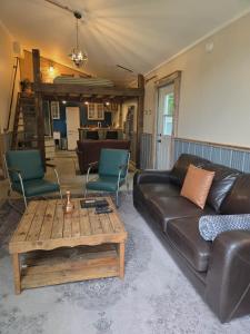 MervilleTiny house & Sauna on Lakefront Farm Oasis的配有皮沙发和咖啡桌的客厅