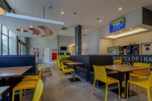 a restaurant with wooden tables and yellow chairs at Nacional Inn Palmas in Palmas