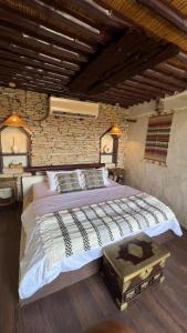 a bedroom with a large bed and a brick wall at نزل حارة المسفاة Harit AL Misfah Inn in Misfāh