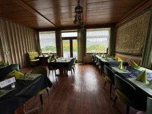 a dining room with tables and chairs and windows at Landgasthaus waldhorn in Forbach