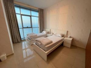two beds in a room with a large window at The Sea Facing Apartment in Ajman 