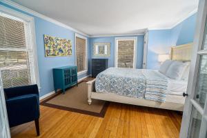 a blue bedroom with a bed and two windows at Butlers Quarters in Saugatuck
