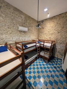 a room with three bunk beds and a stone wall at Casa Aguazul in Campeche