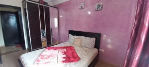 a bedroom with a bed with a pink wall at Mohammed V International Airport RAHMANI in Nouaseur