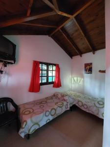 a bedroom with a bed and a window with red curtains at Un lugar en el Mundo in Villa Amancay