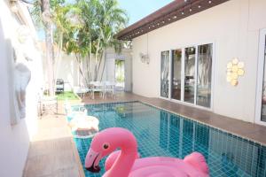 a swimming pool with pink inflatable flamingos in a house at The Pool House Pattaya No.8 in Pattaya South