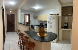 a kitchen with a counter with chairs and a refrigerator at AP Completo Tabatinga in Nísia Floresta