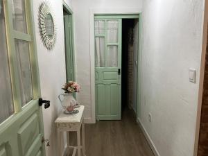 ein Flur mit einer grünen Tür und einem Tisch mit Blumen darauf in der Unterkunft La Casita in Arenas de San Pedro + 21 Fotos