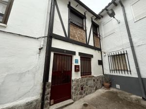 ein weißes Gebäude mit einer roten Tür drauf. in der Unterkunft La Casita in Arenas de San Pedro