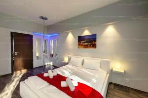 a bedroom with a large white bed with a red blanket at Arcanum Apartman in Makó