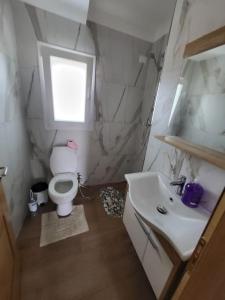 a bathroom with a toilet and a sink and a window at Villa Xhovi 2 in Ishull-Lezhë +12 photos