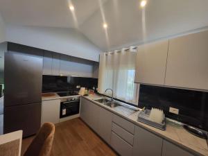 a kitchen with white cabinets and black appliances at Villa Xhovi 2 in Ishull-Lezhë