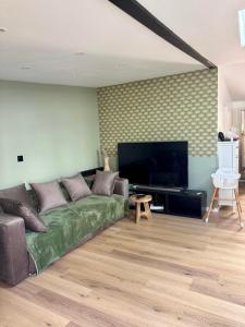 ein Wohnzimmer mit einem grünen Sofa und einem Flachbildfernseher in der Unterkunft Cosy House Near DisneyLand Paris in Roissy-en-Brie