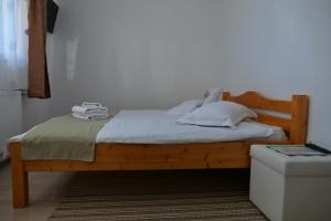 una camera con letto in legno e lenzuola bianche di Pensiunea Tiplea a Ocna Şugatag