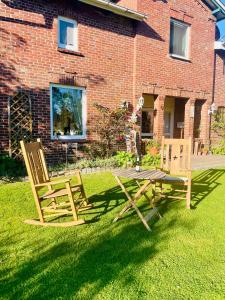 two wooden chairs and a picnic table in a yard at Ruge Apartment in Sankt Michaelisdonn