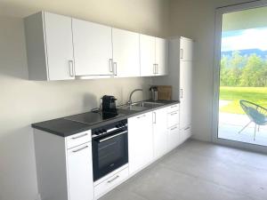 a kitchen with white cabinets and a sink and a window at Appartement calme et moderne in Estavayer-le-Lac