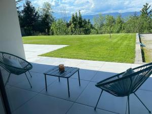 a patio with two chairs and a table and a field at Appartement calme et moderne in Estavayer-le-Lac